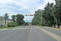 A photograph of a Pedestrian Hybrid Beacon (PHB) at a crossing in Alexandria, VA. The lights are showing flashing red lenses.